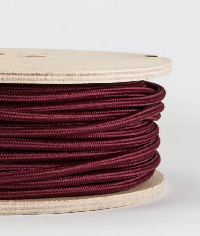 closeup of burgundy fabric cable on reel against white background