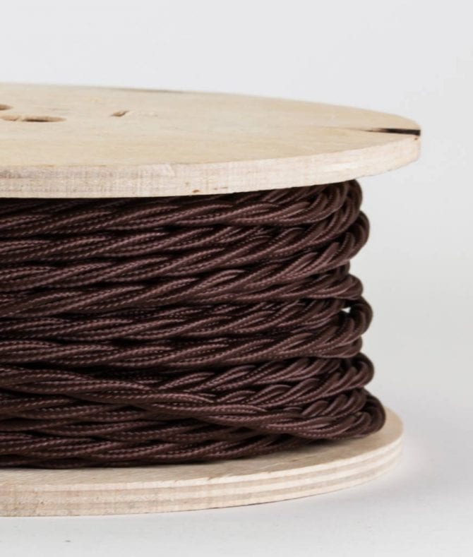 closeup of brown twisted fabric cable on reel against white background