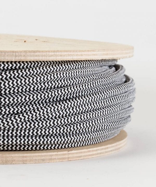 closeup of black and white fabric cable on reel against white background