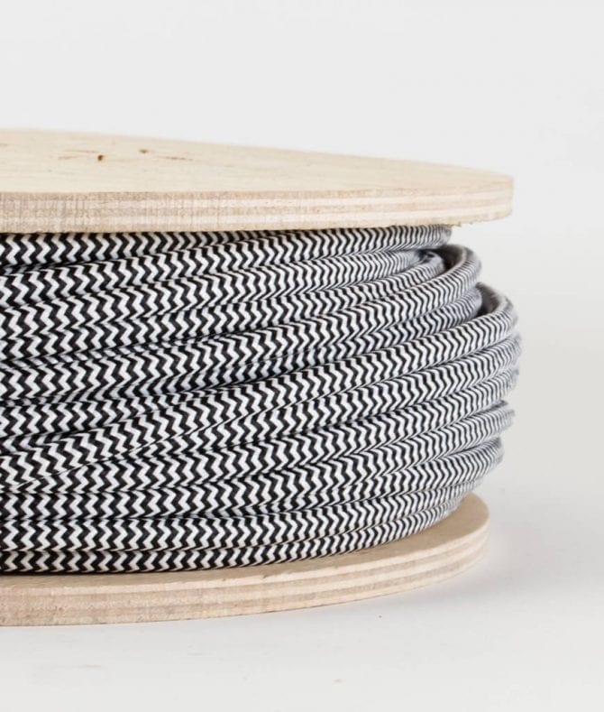 closeup of black and white fabric cable on reel against white background