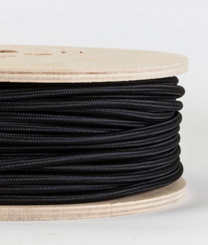 closeup of black fabric cable on reel against white background