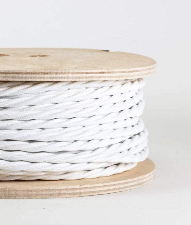 closeup of white twisted fabric cable on reel against white background