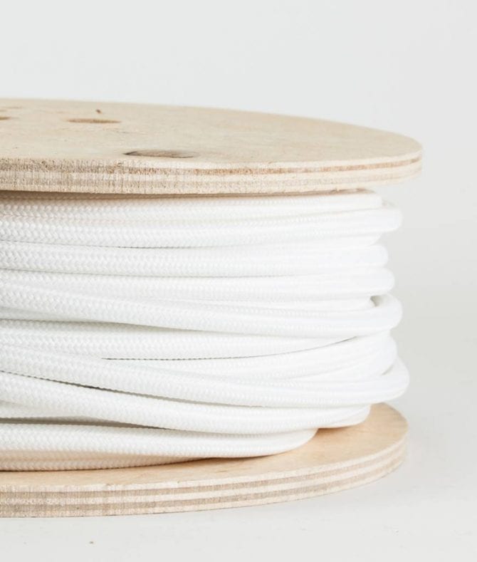 closeup of white fabric cable on reel against white background