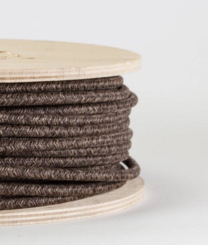 closeup of brown jumper fabric cable on reel against white background