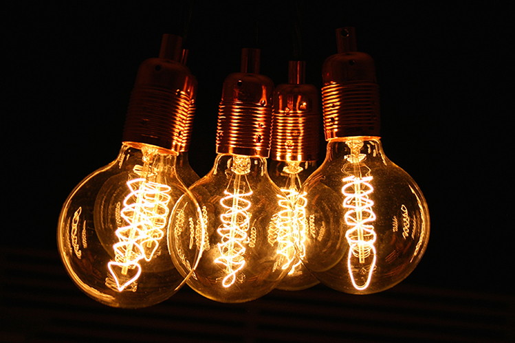 filament globe light bulbs suspended in a cluster against black background