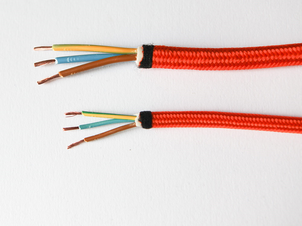 orange fabric electrical cable against white background