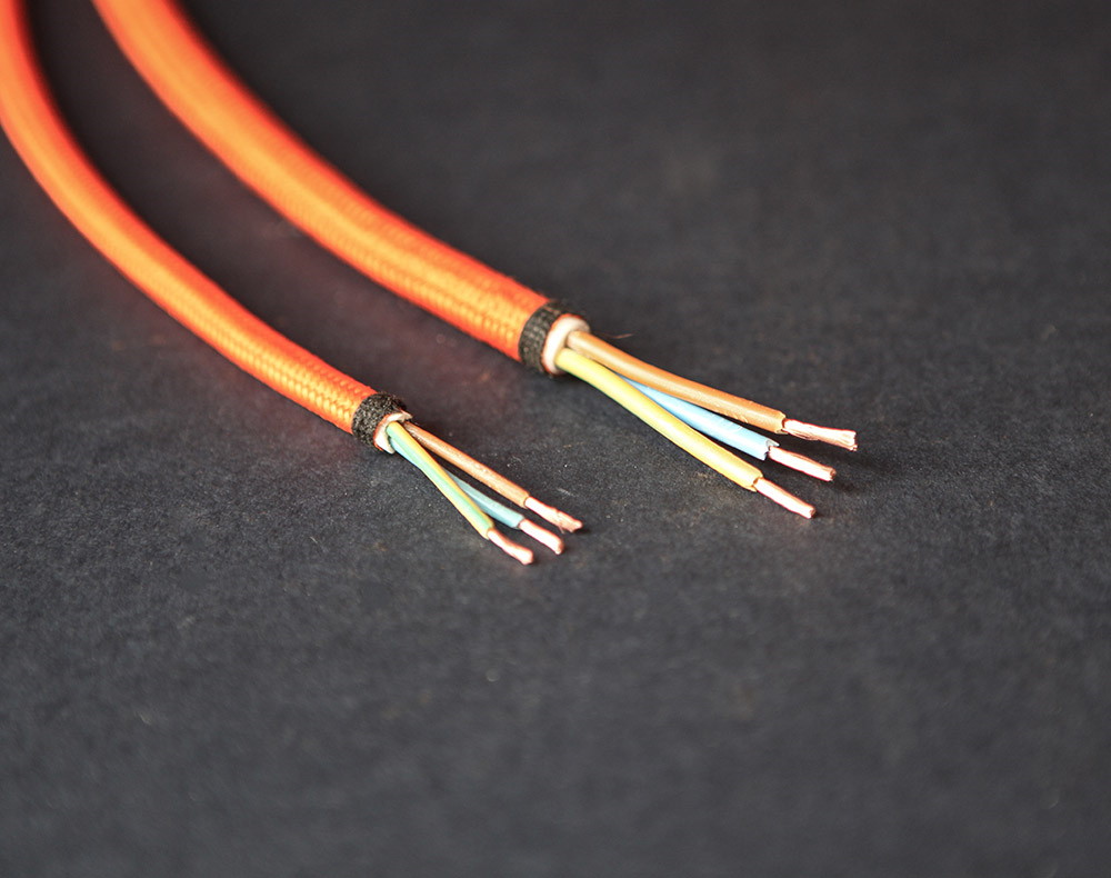 fabric cable explained - a length of fabric lighting cable and mains cable with exposed wires against black background