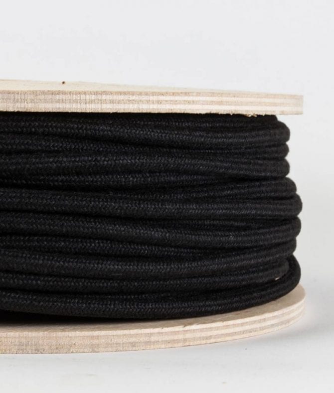 closeup of matt black fabric cable on reel against white background