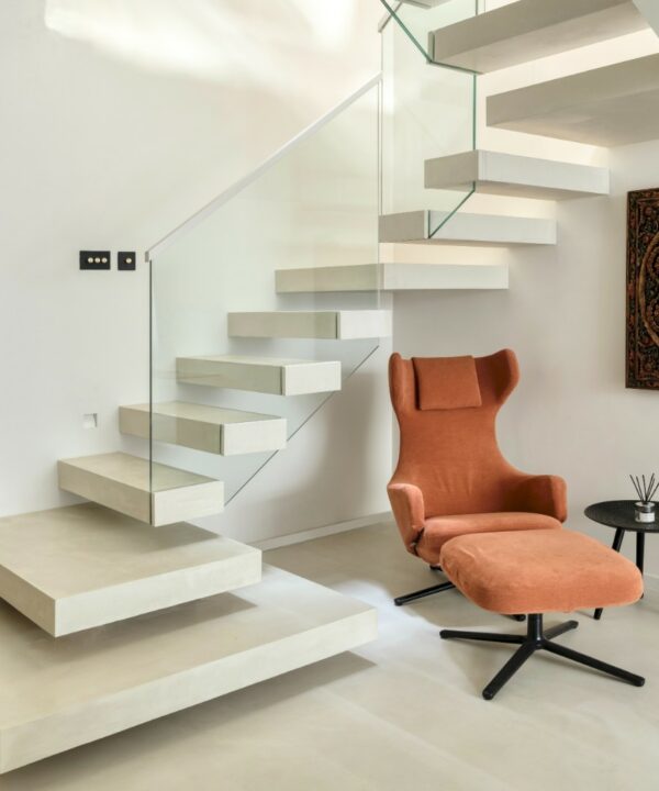 black and gold dimmer switches installed on a white floating stairway in a minimalist hallway