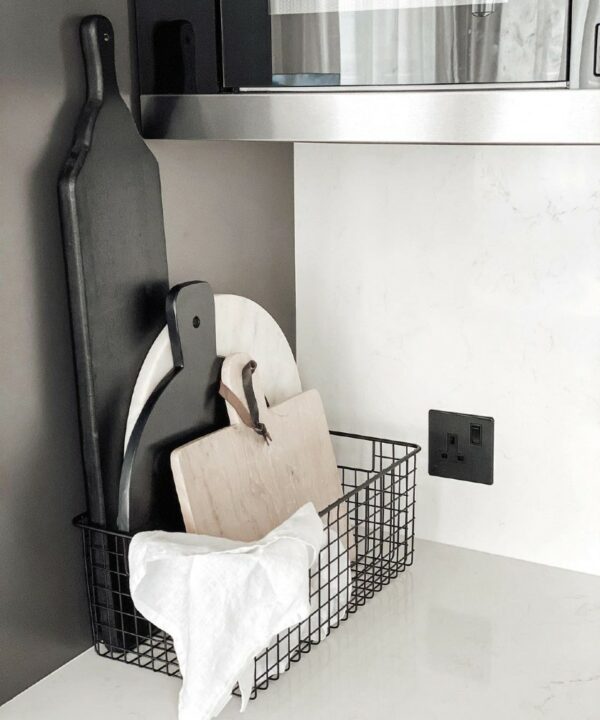 black single socket installed on a white wall in a white and grey kitchen