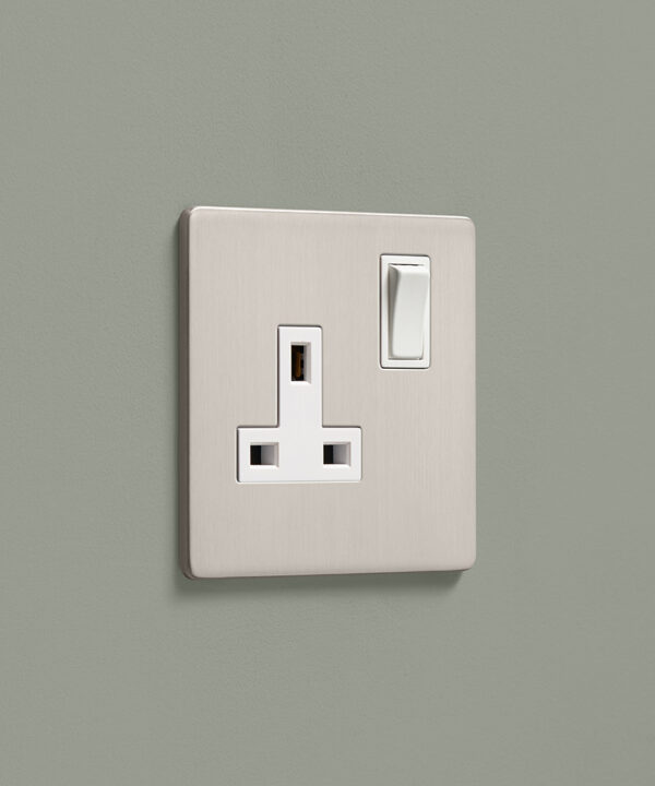 brushed silver single 1 gang plug socket on a sage green wall