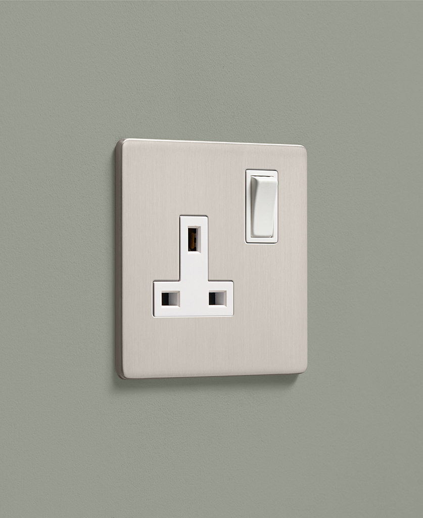 brushed silver single 1 gang plug socket on a sage green wall