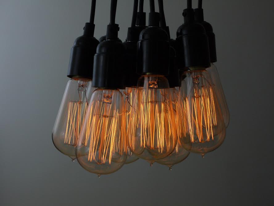 squirrel cage filament bulbs suspended from black bakelite bulb holders against grey background