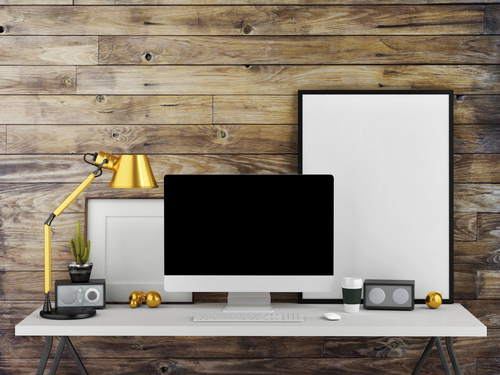 white desk with white computer and brass lamp against wooden panelled wall