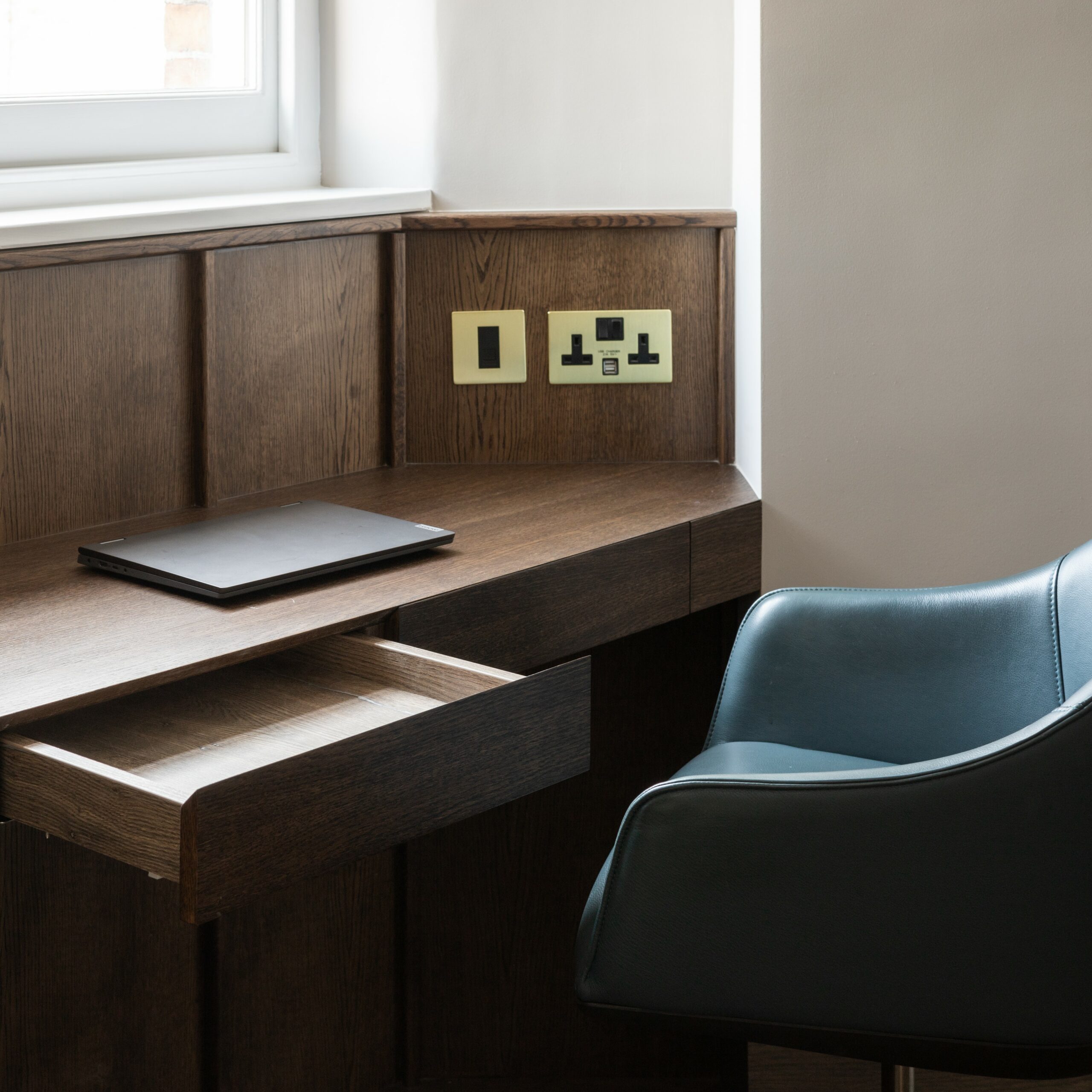 gold and black double socket with usb on wooden cladded built in desk