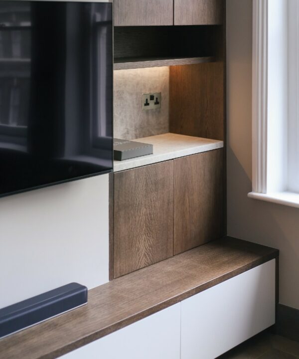 gold and black double socket installed on a dark wooden wall besides a TV