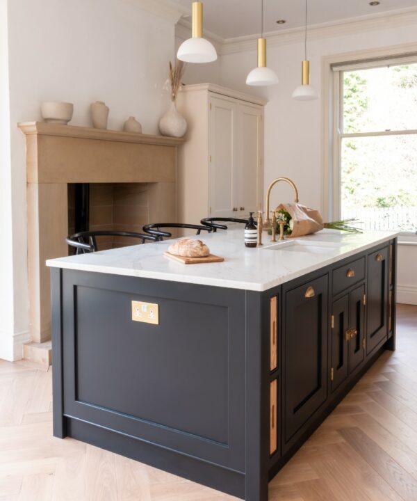 gold and white double plug socket installed on a dark grey kitchen island in an off white kitchen
