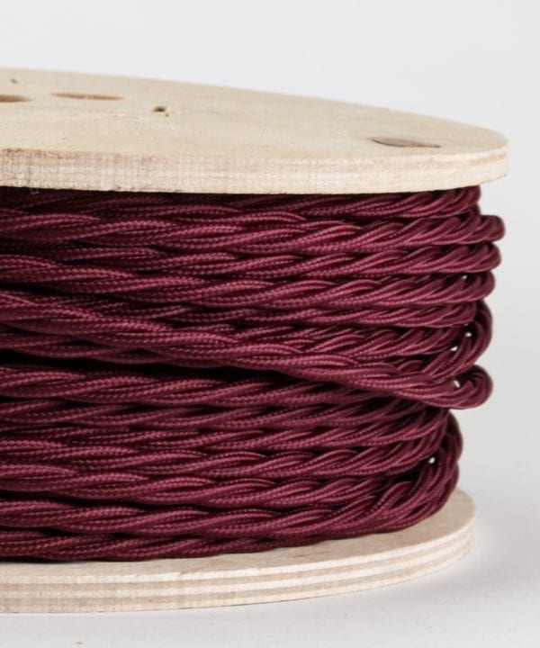 closeup of burgundy twisted cable on reel against white background