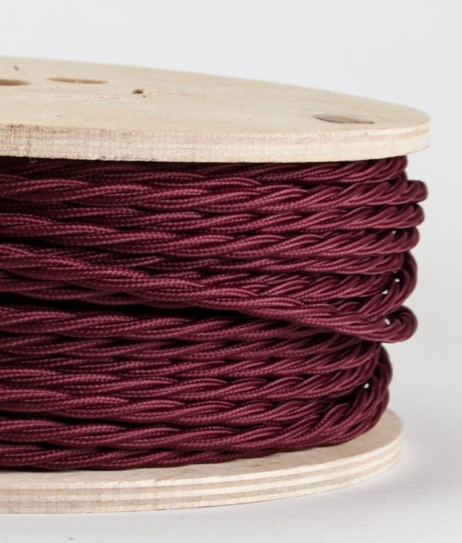closeup of burgundy twisted cable on reel against white background