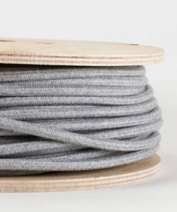 closeup of felt grey fabric cable on reel against white background