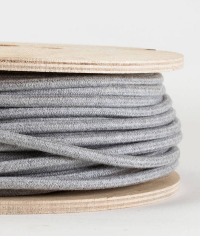 closeup of felt grey fabric cable on reel against white background