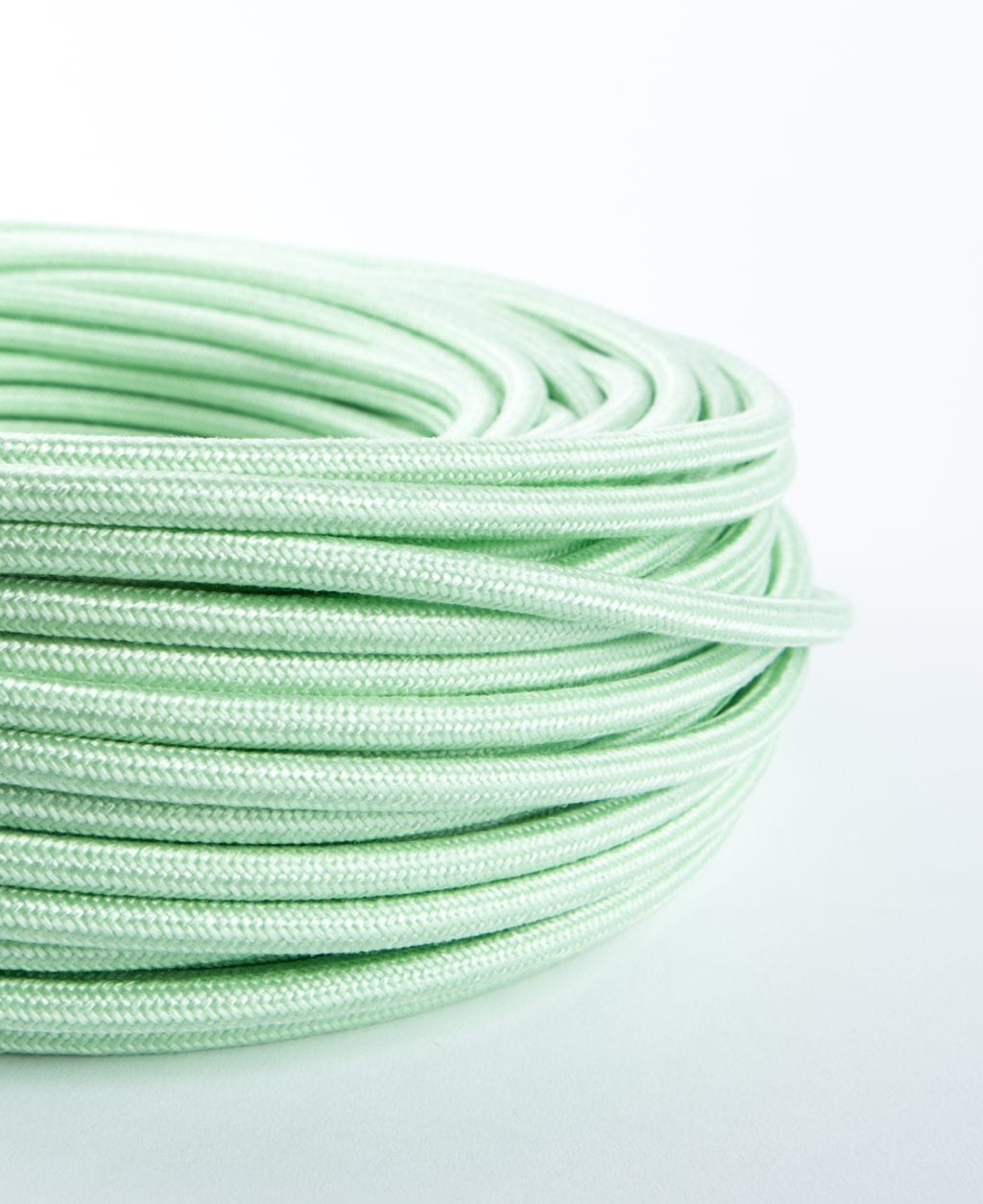 close up of mint green fabric cable coil on white background