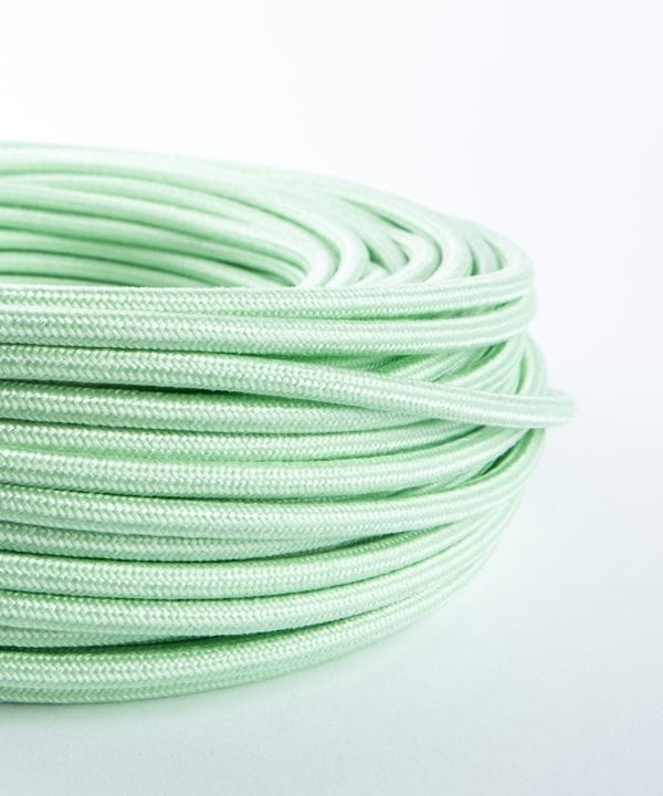 close up of mint green fabric cable coil on white background