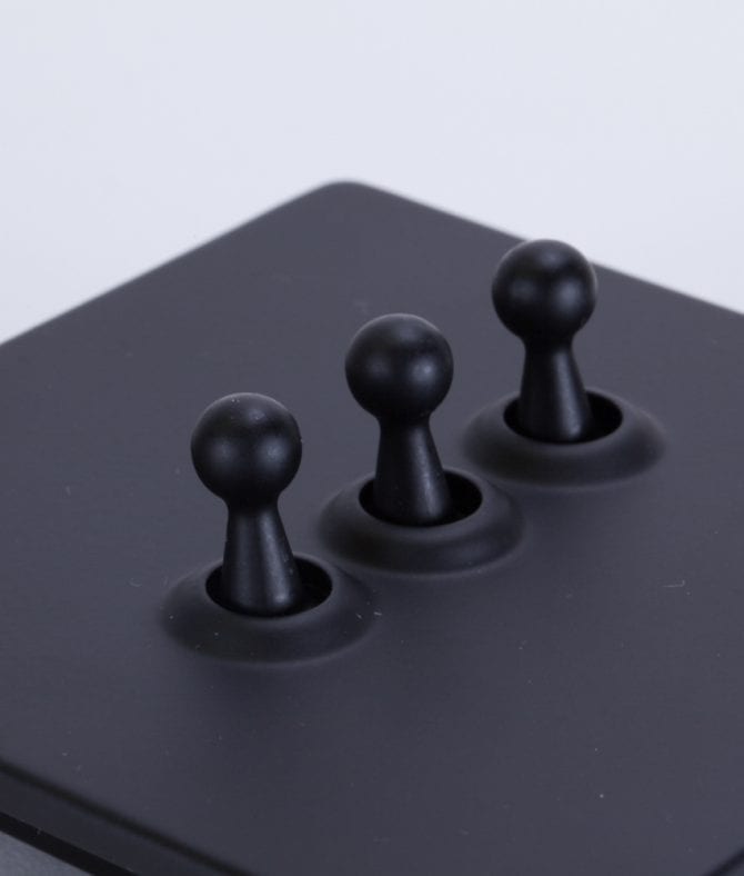 closeup of black and black triple toggle switch against white background