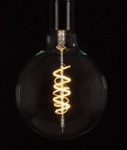 extra large led globe bulb with spiral filament against black backgroubd