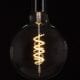 extra large led globe bulb with spiral filament against black backgroubd
