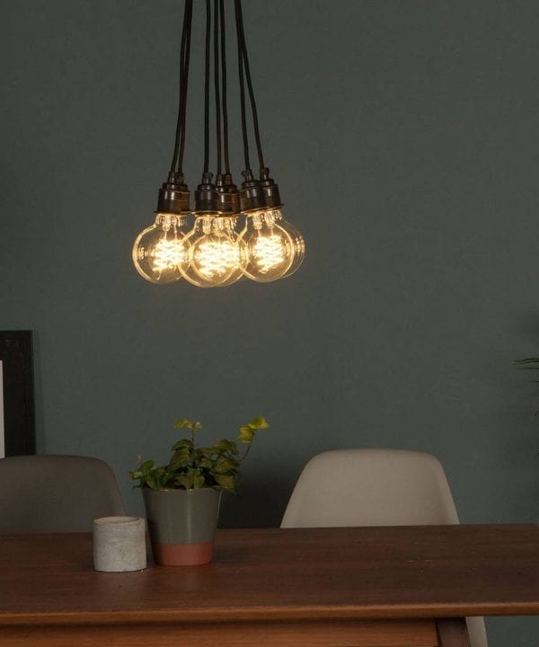 led globe bulb suspended in a cluster above a table against grey wall