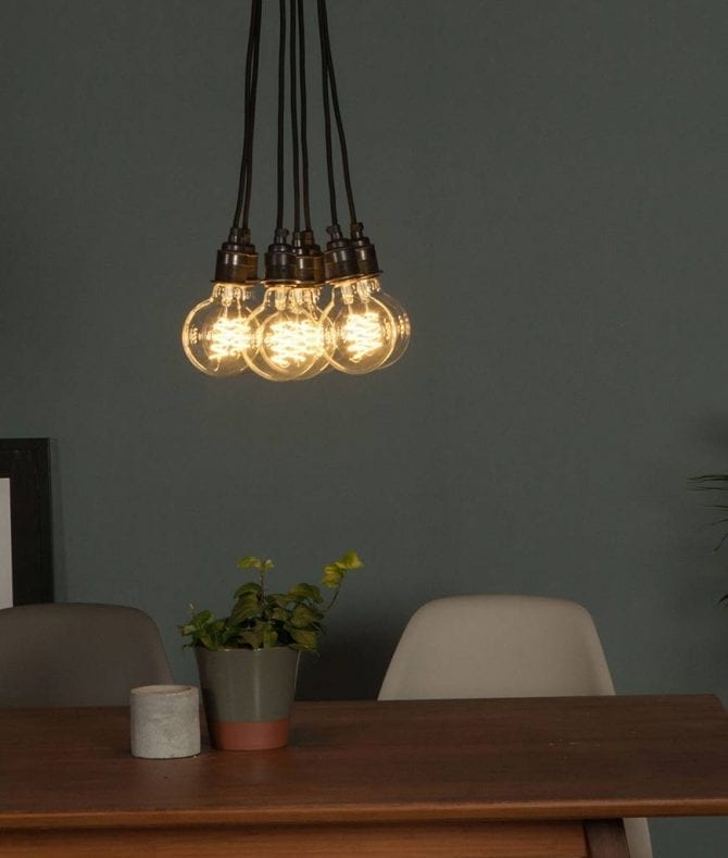 led globe bulb suspended in a cluster above a table against grey wall