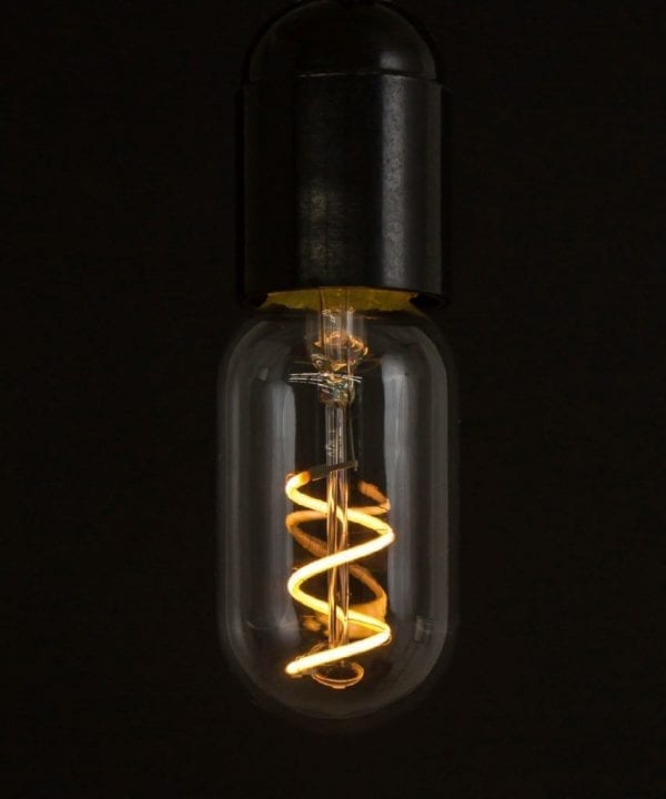 radio valve led filament bulb with loose spiral filament lit suspended from bakelite bulb holder against black wall