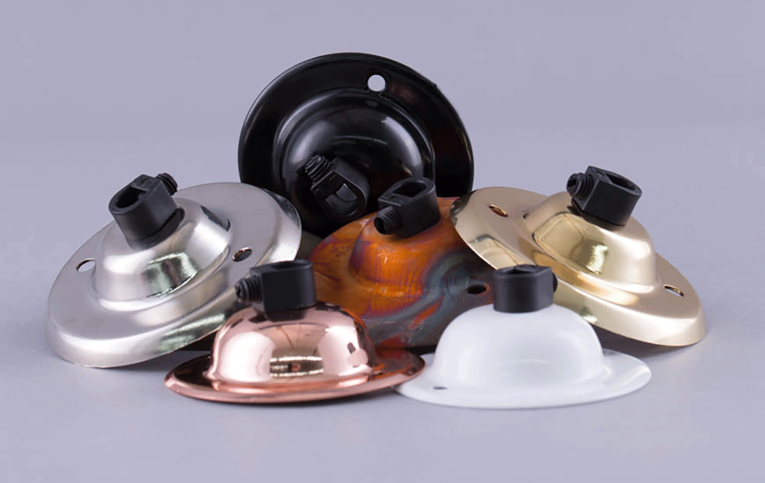 group shot of silver, copper, tarnished copper, black, gold and white ceiling roses against grey background