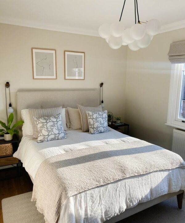 pag wall lamps installed either side of a bed in a neutral bedroom