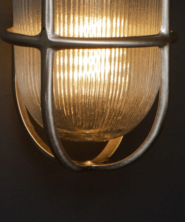 closeup of lit simon silver bulkhead light against black background