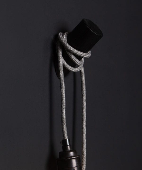 peg wall light black with grey jumper cable against black wall closeup