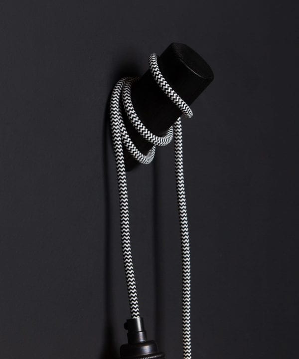 peg wall light black with mint humbug cable against black wall closeup
