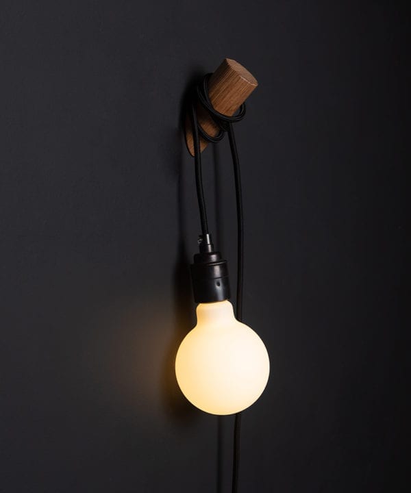 danish oil peg lamp with black cable on black wall