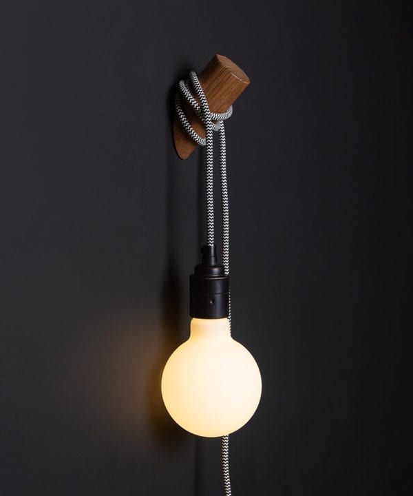 danish oil peg lamp with mint humbug cable against black wall