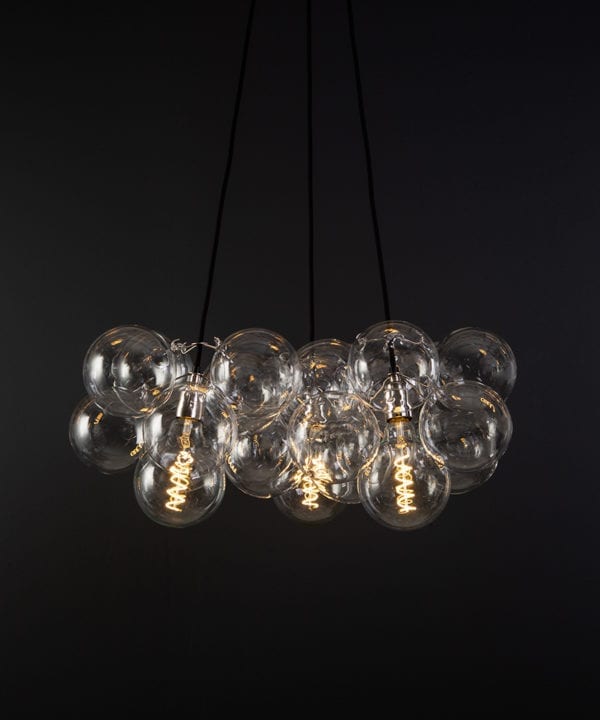 bubble pendant chandelier with 24 clear glass baubles and 3 silver bulb holders suspended from black fabric cable against a black wall