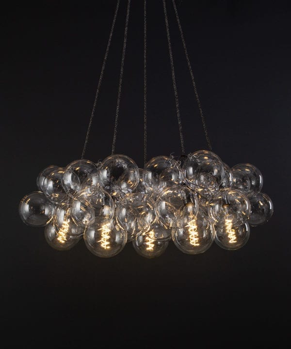 bubble glass chandelier with 40 glass baubles & 5 bronze bulb holders suspended from textured fabric cable against a black wall