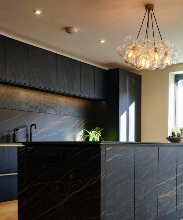 large clear bubble chandelier suspended above a large black marble kitchen island