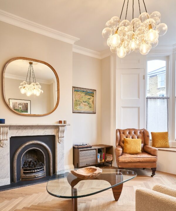 large clear bubble chandelier suspended above a glass and wood coffee table in an off-white living room