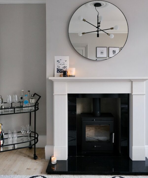 reflection of a black tinkisso pendant light in a round mirror in an off-white living room