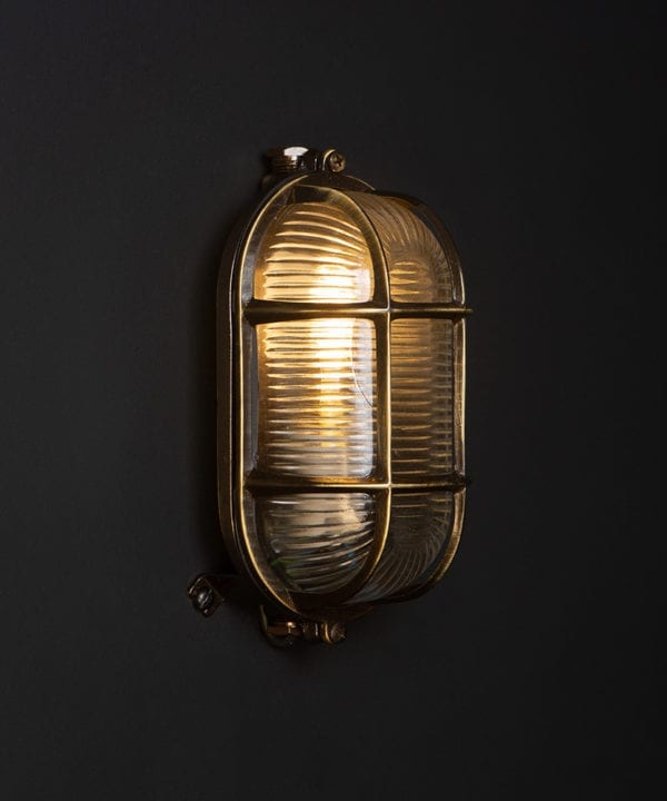 dave lit aged brass outdoor bulkhead light on black wall