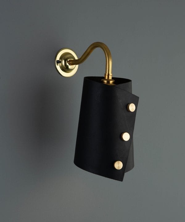 polished brass wall sconce lighting with black leather light shade on grey wall
