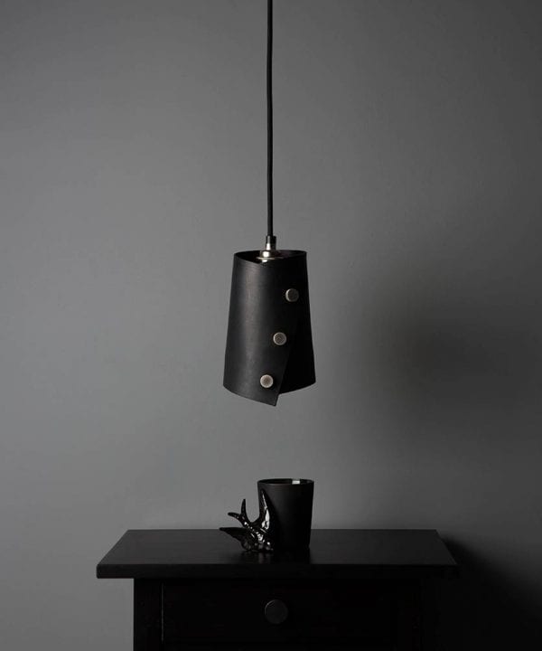 leather finish cuff pendant with black leather shade secured with knurled silver knobs, black fabric cable against dark grey background lifestyle