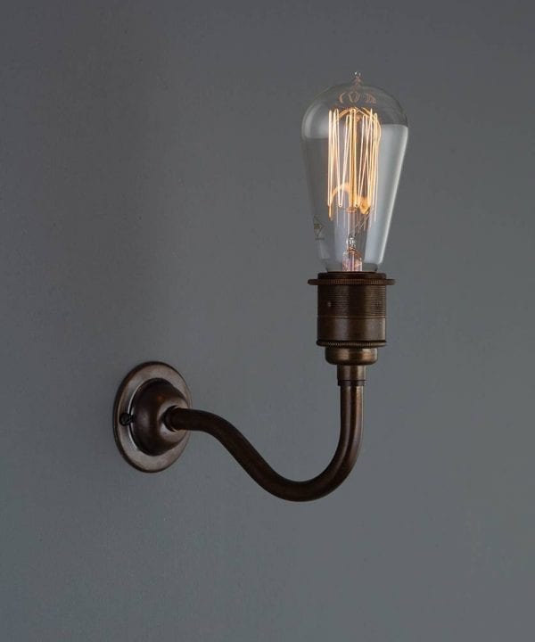 bramley brewer's brass wall sconce with lit filament bulb against grey wall