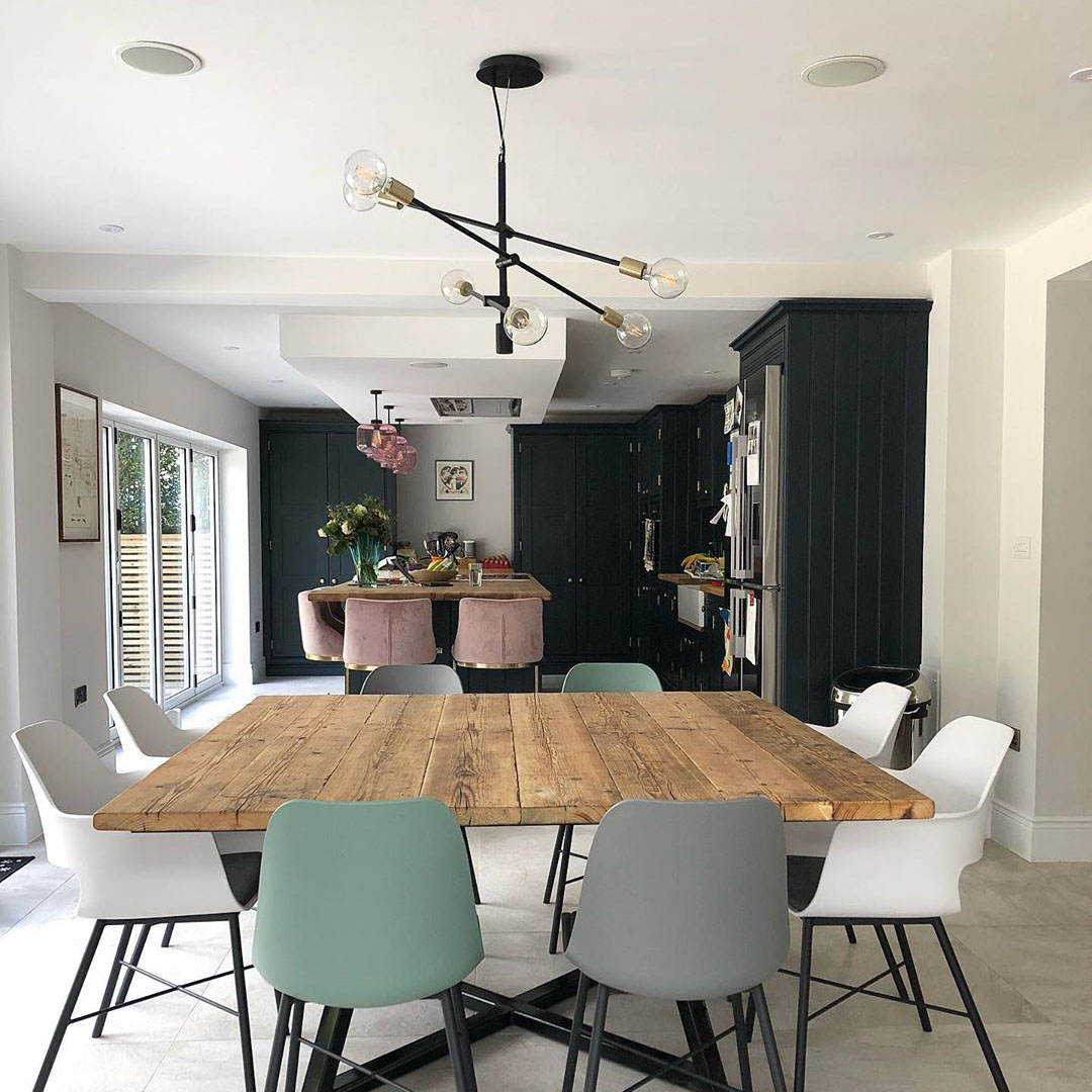 Trikonasana black multi-arm light suspended over a wooden dining table in a black and white kitchen